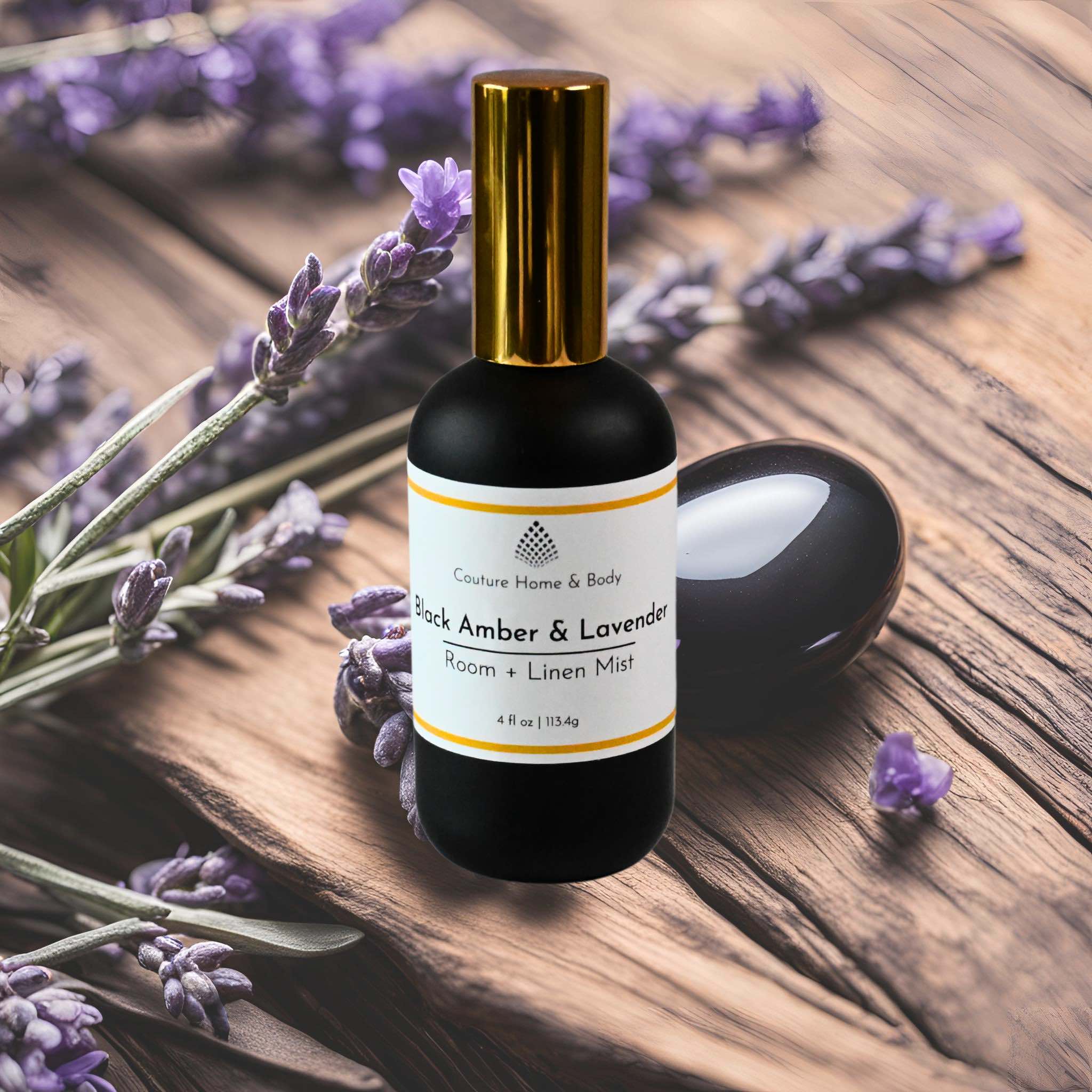 A sleek black bottle with a gold cap labeled "Black Amber & Lavender Room + Linen Mist" from Couture Home & Body. A sleek black bottle with a gold cap labeled "Black Amber & Lavender Room + Linen Mist" from Couture Home & Body.