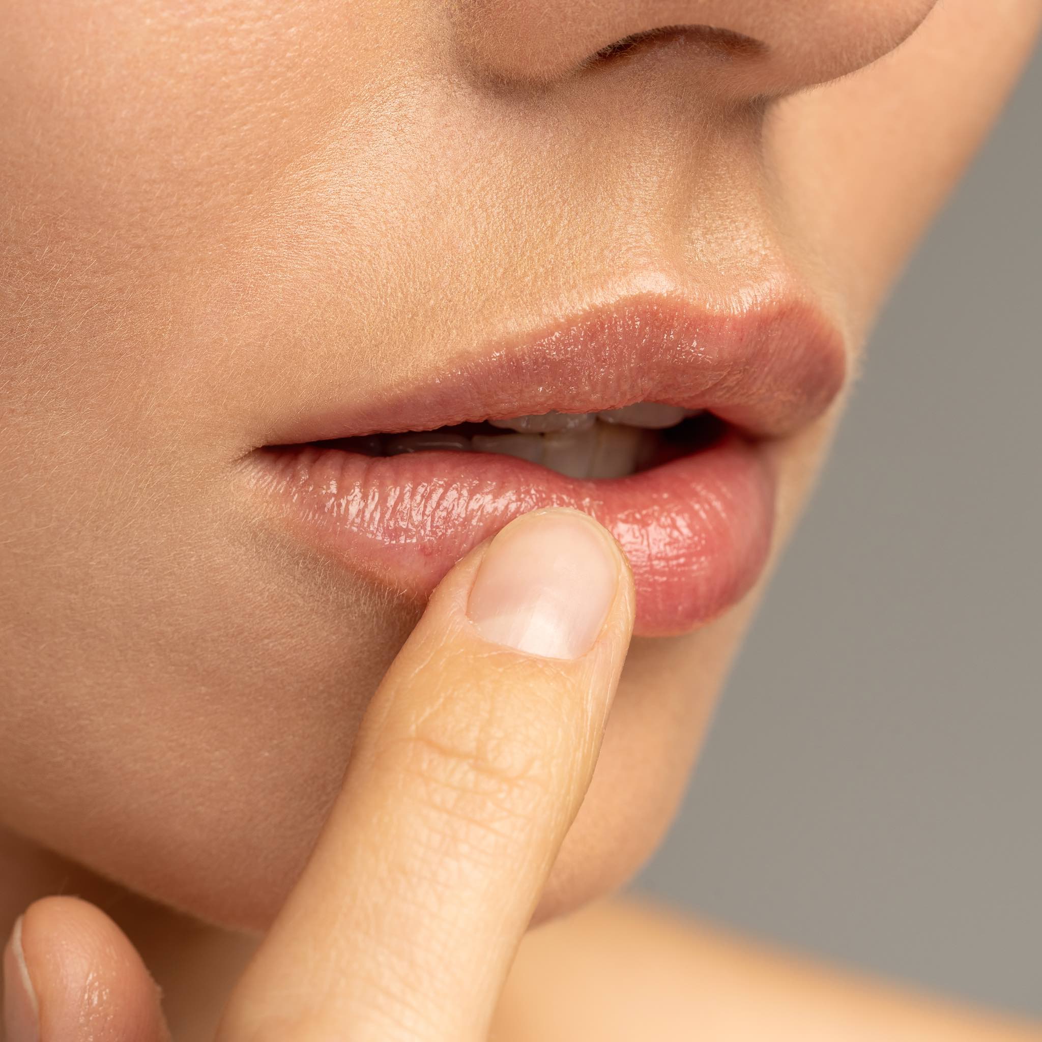 Close-up of a woman applying nourishing lip balm to her lips.