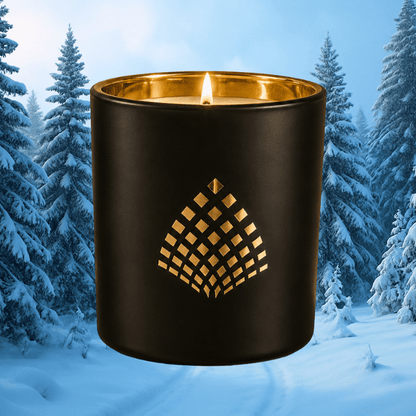 A black candle with a gold interior shown lit against a snowy winter forest background.