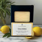 Citrus Verbena soap bar in packaging with lemons and a plant on a marble surface.
