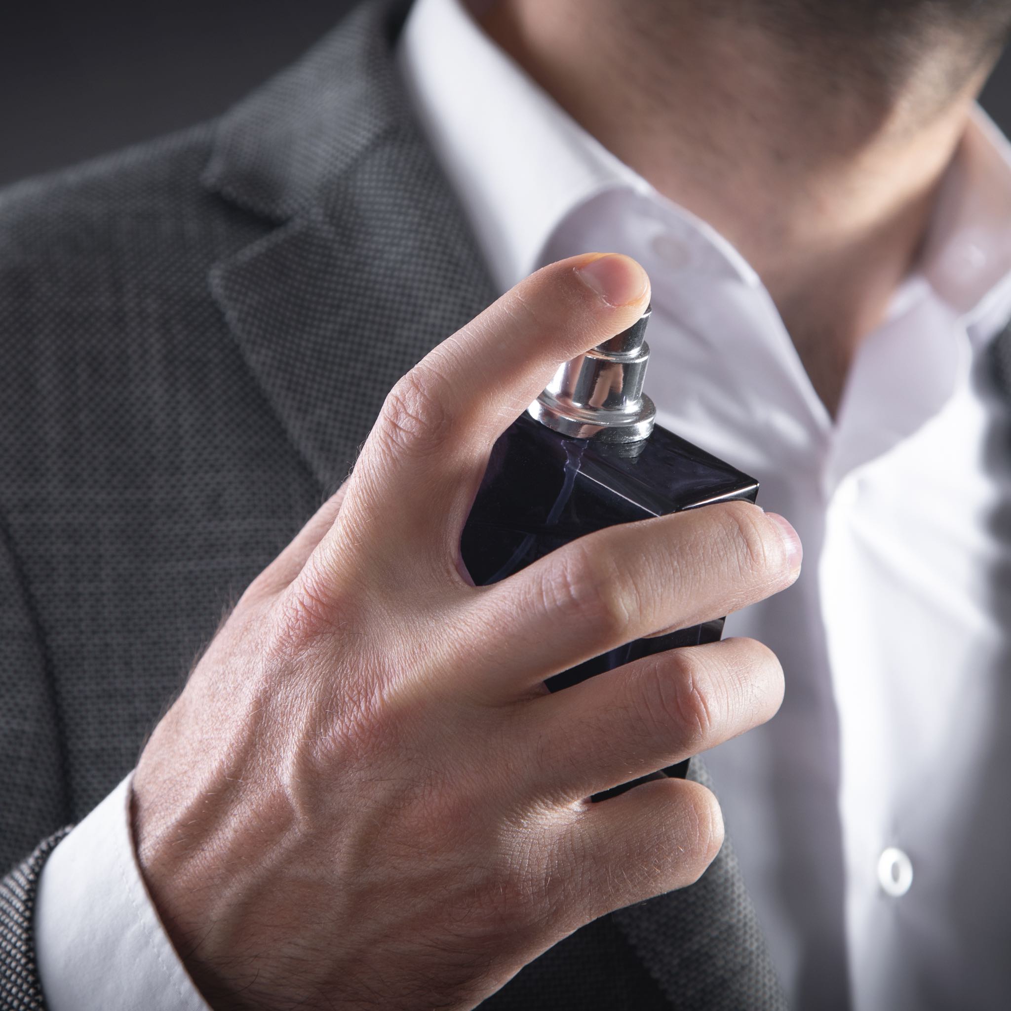 Man in a sharp suit applying cologne, capturing the essence of sophistication and elegance.