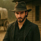 Man wearing a brown hat and dark coat in a dusty, possibly Western setting.