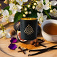 Luxury home fragrance-Golden Hour candle infused with black tea, fig, and clove in a matte black glass jar with gold interior.