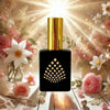 Perfume bottle with gold cap and black square design surrounded by flowers and soft lighting