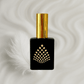 Black perfume bottle with gold cap on a milky background next to a feather.