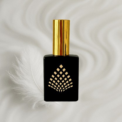Black perfume bottle with gold cap on a milky background next to a feather.