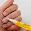 A hand applying cuticle oil using a brush applicator from Couture Home & Body.