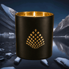 Black luxury candle with gold interior set against a snowy mountain lake at night.