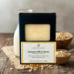 Oatmeal Milk & Honey soap bar in packaging with oats and milk on a wooden surface.