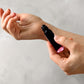 Close-up of hands applying perfume oil with a rollerball to the wrist, showcasing a personal and intimate fragrance moment.