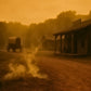 Vintage wagon on a dirt road with wooden buildings in the background, all bathed in an orange hue.