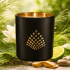 Black candle holder with gold interior on a natural background with flowers and leaves.