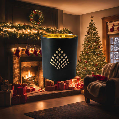 A black and gold Couture Home & Body candle set against a cozy Christmas scene with a lit fireplace, stockings, and a glowing tree surrounded by presents, evoking the warm, festive spirit of the Yuletide candle.